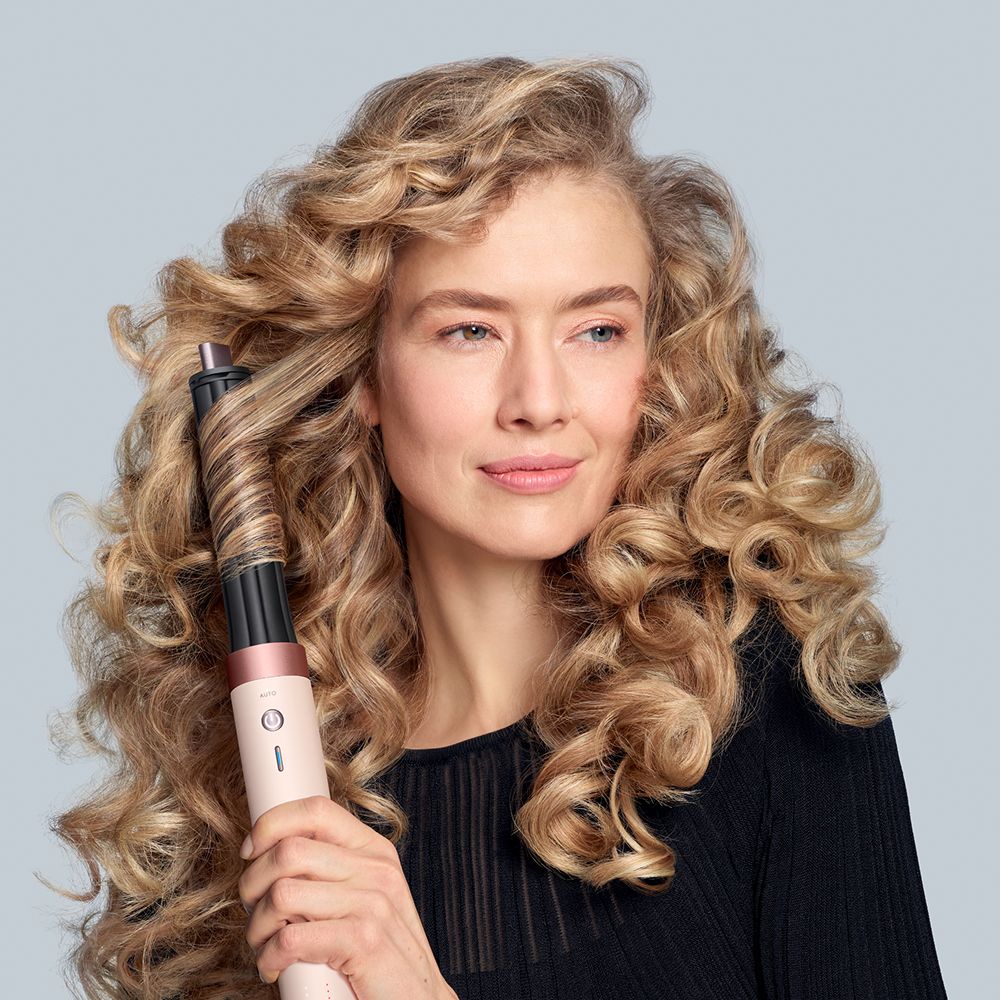 A model uses the Dyson Airwrap ID multi-styler and dryer to curl her hair.